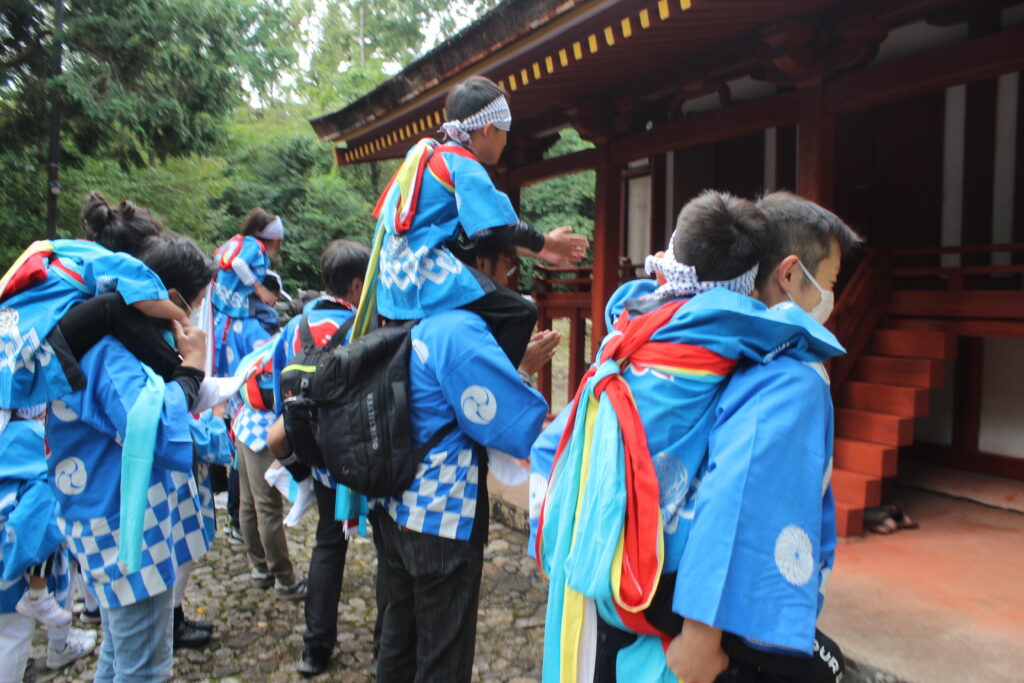 八幡神社の本殿の前で 肩車された乗り子たちが拝んでいます 